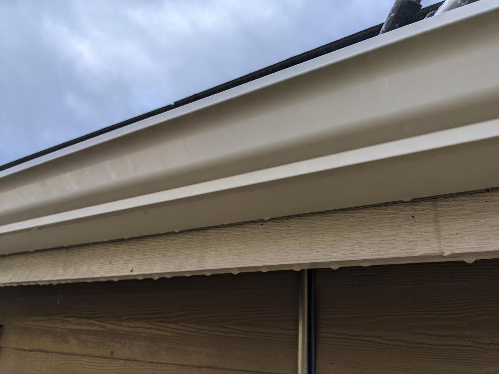 A close up of a gutter on the side of a house.