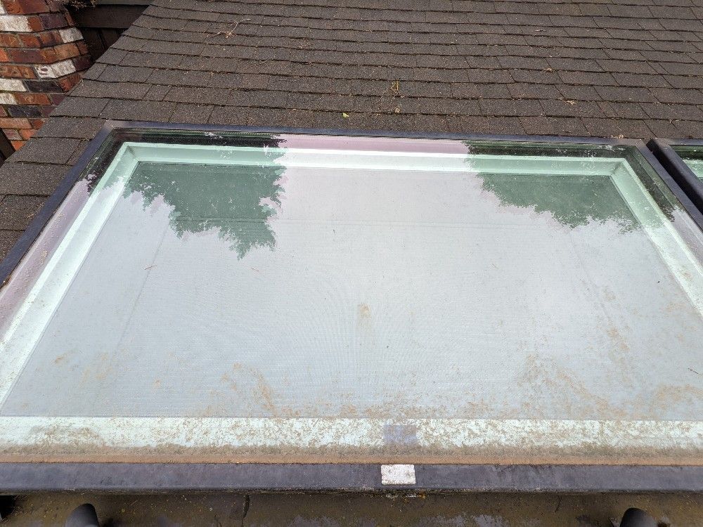 A skylight is sitting on top of a brick roof.