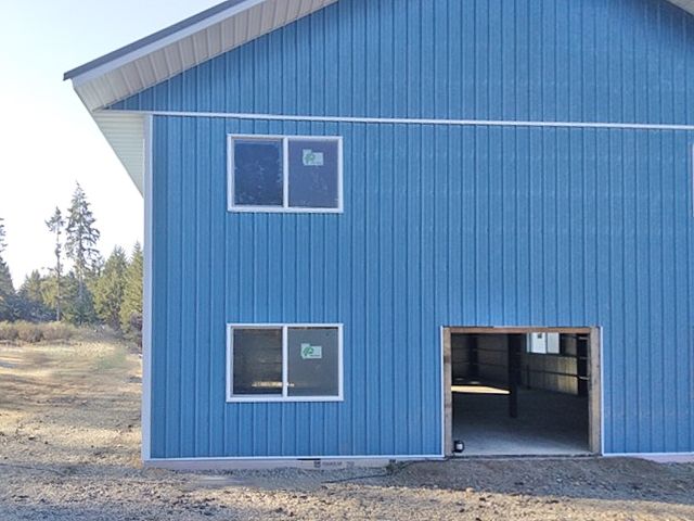A two-story warehouse workshop has blue standing seam metal siding.