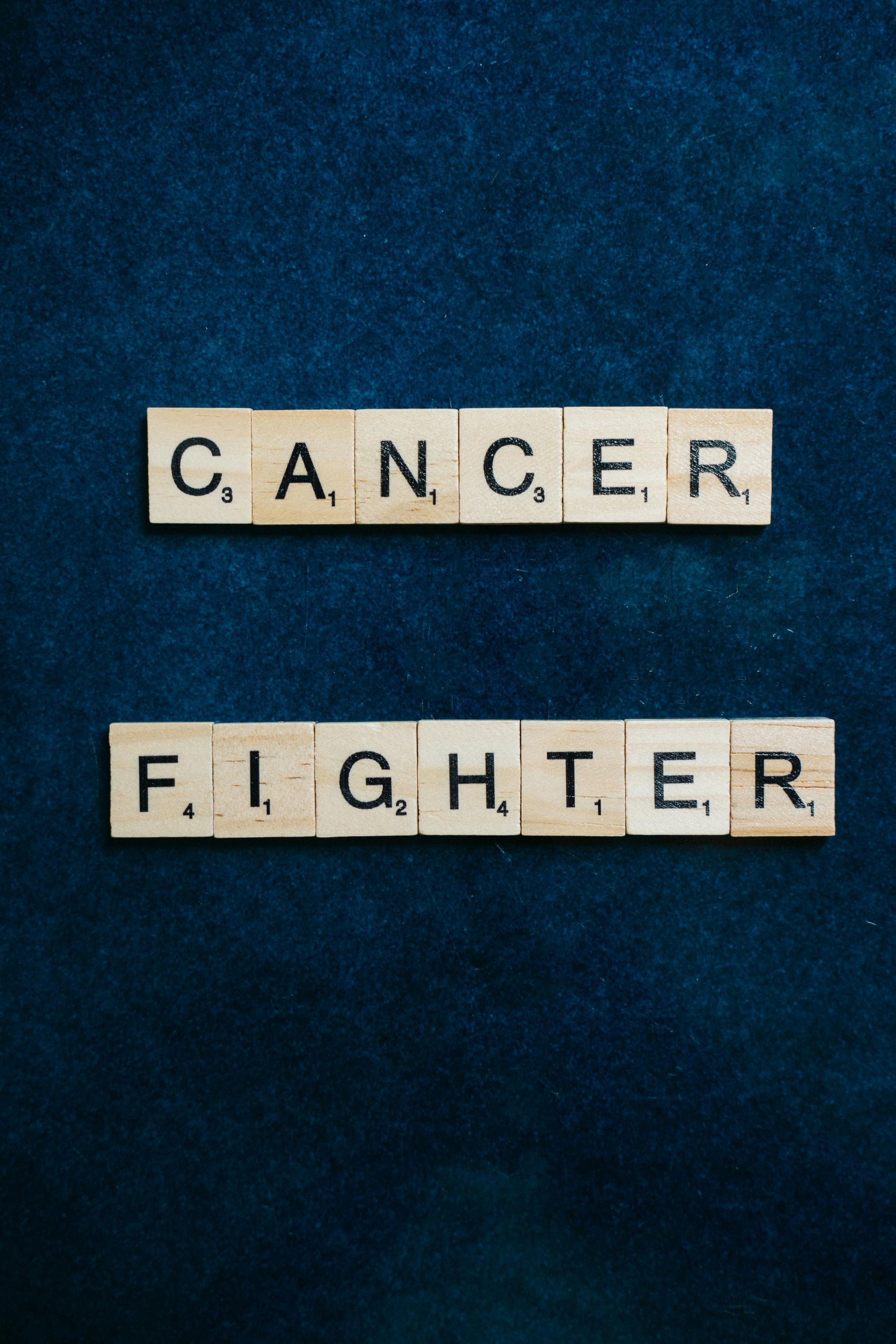 Scrabble tiles that say cancer fighter on a blue background