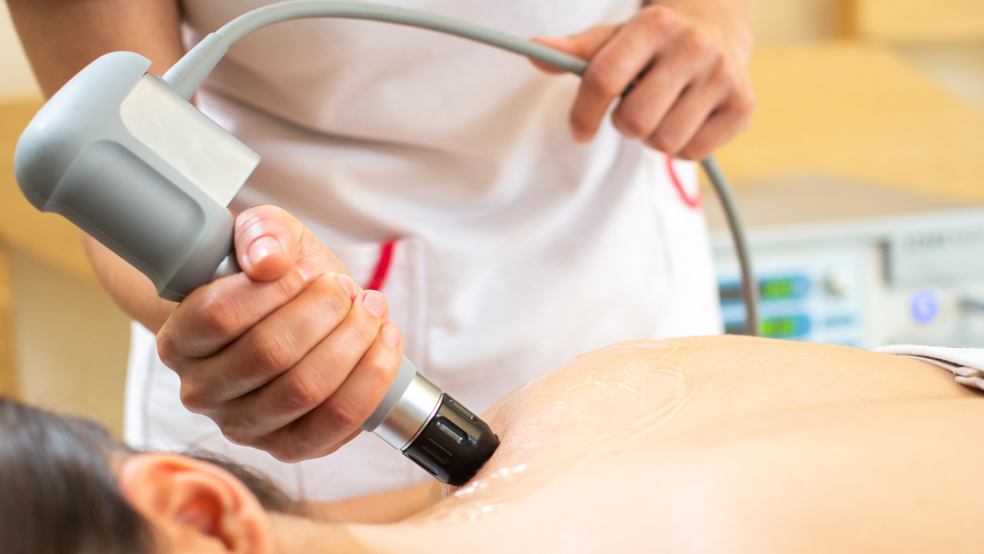 A medical professional administering ultrasound therapy to a patient's back.