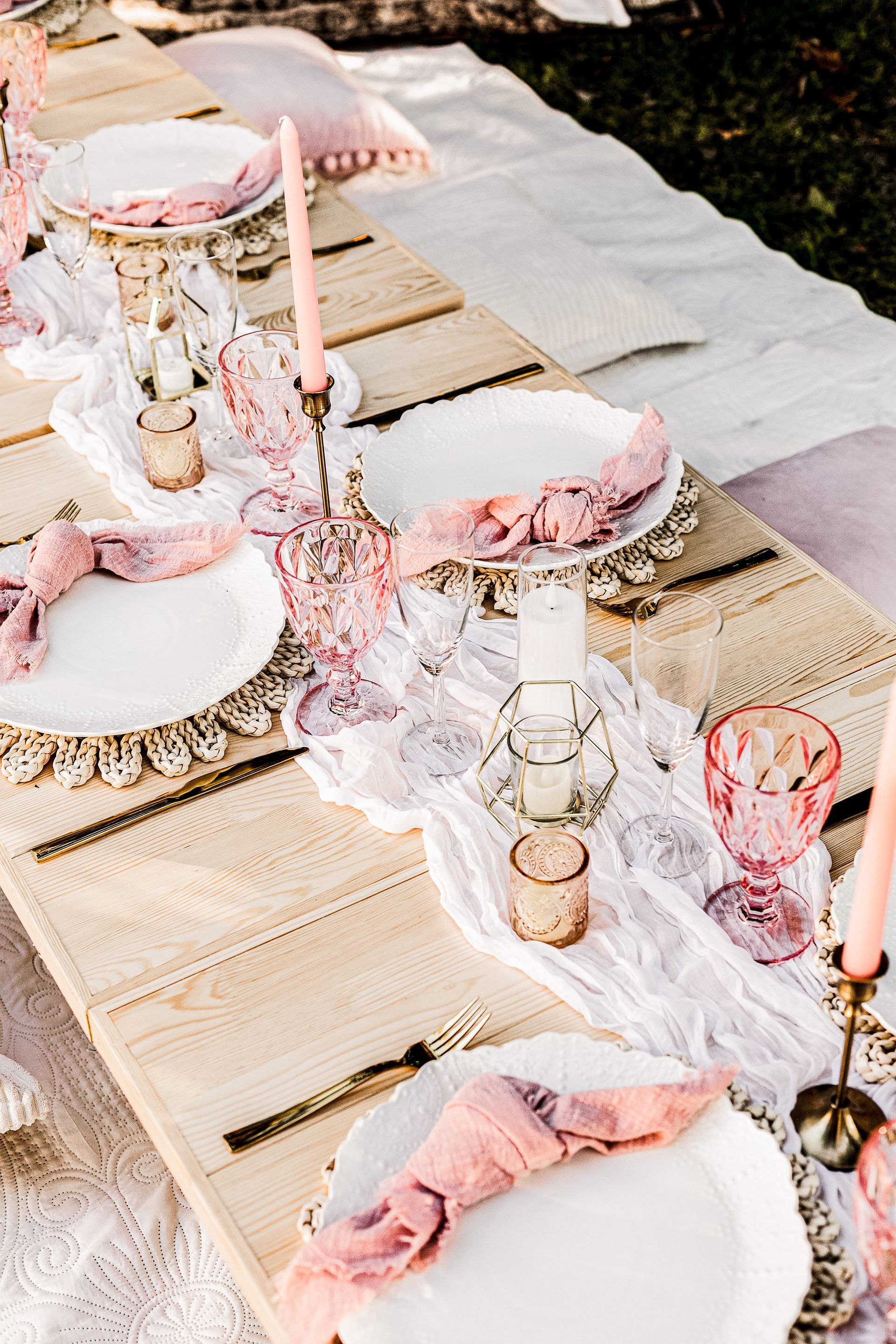 A wooden table with plates , candles , and napkins on it.