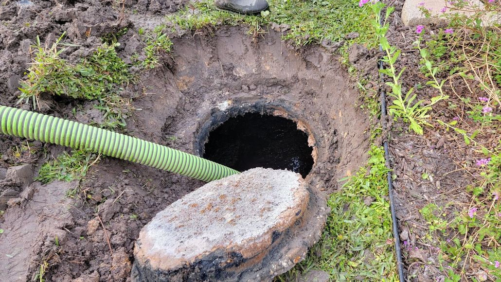 A green hose is coming out of a septic tank.