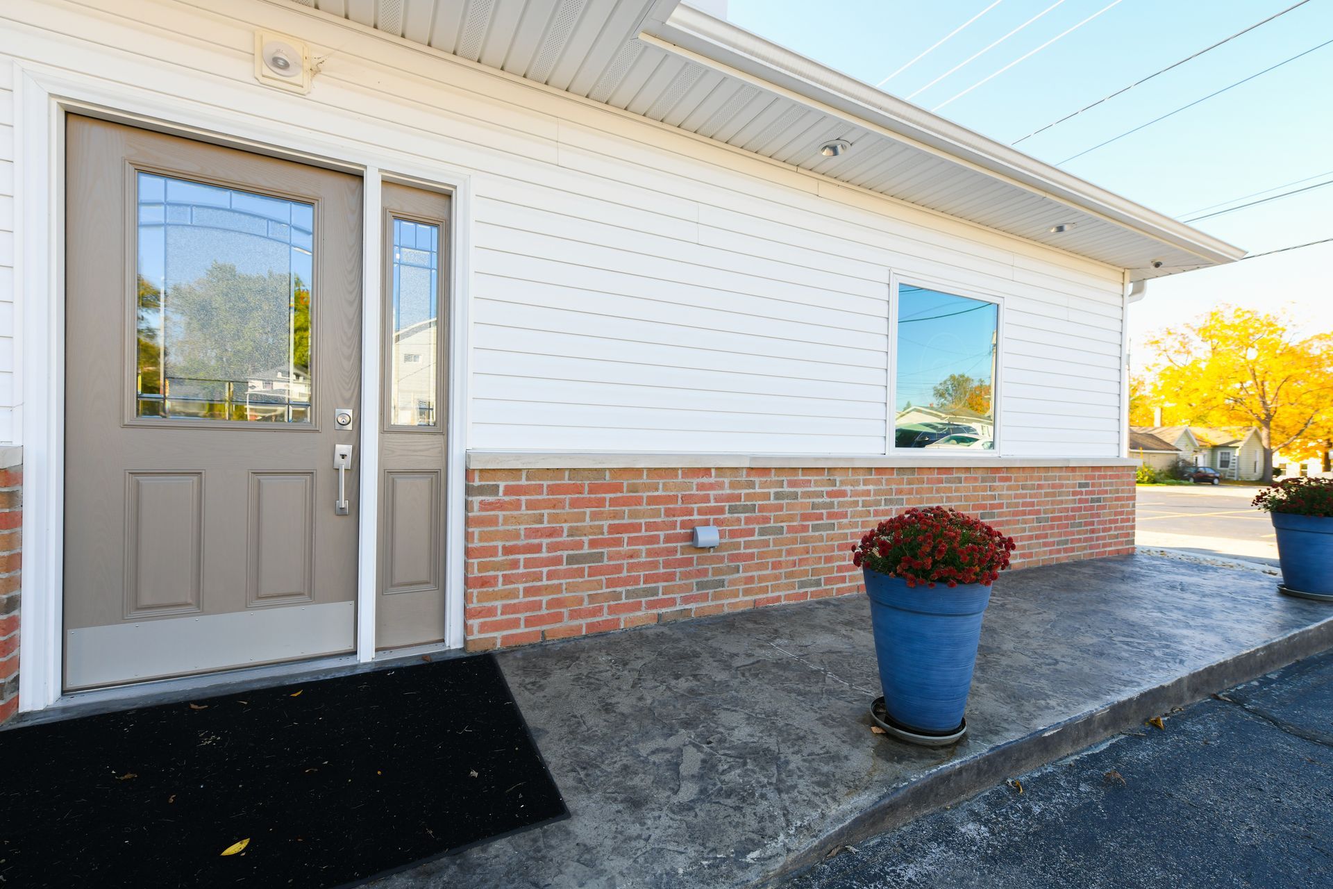 A brick building with a brown door and two blue potted plants in front of it.