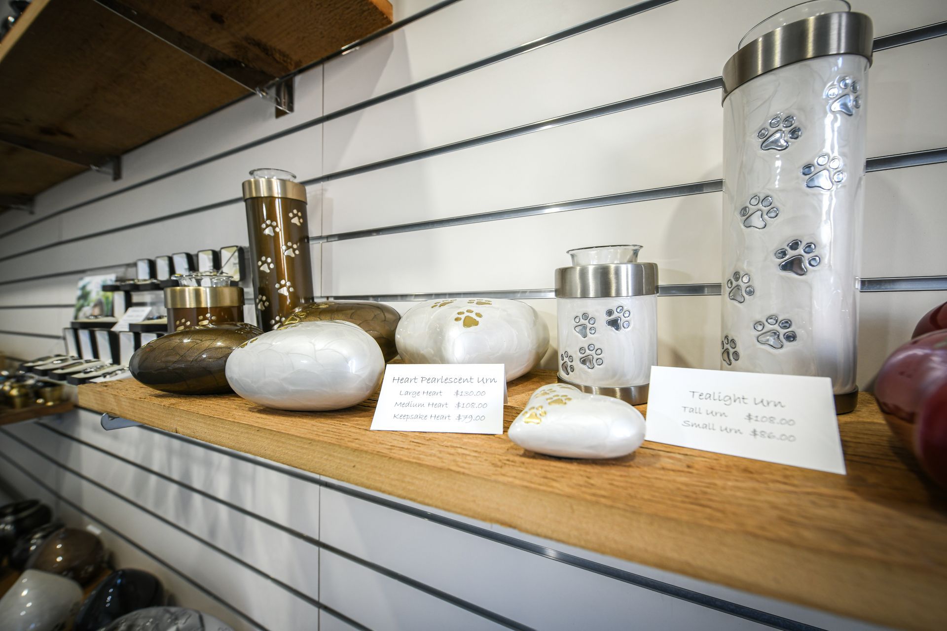 A shelf filled with vases and urns with paw prints on them.