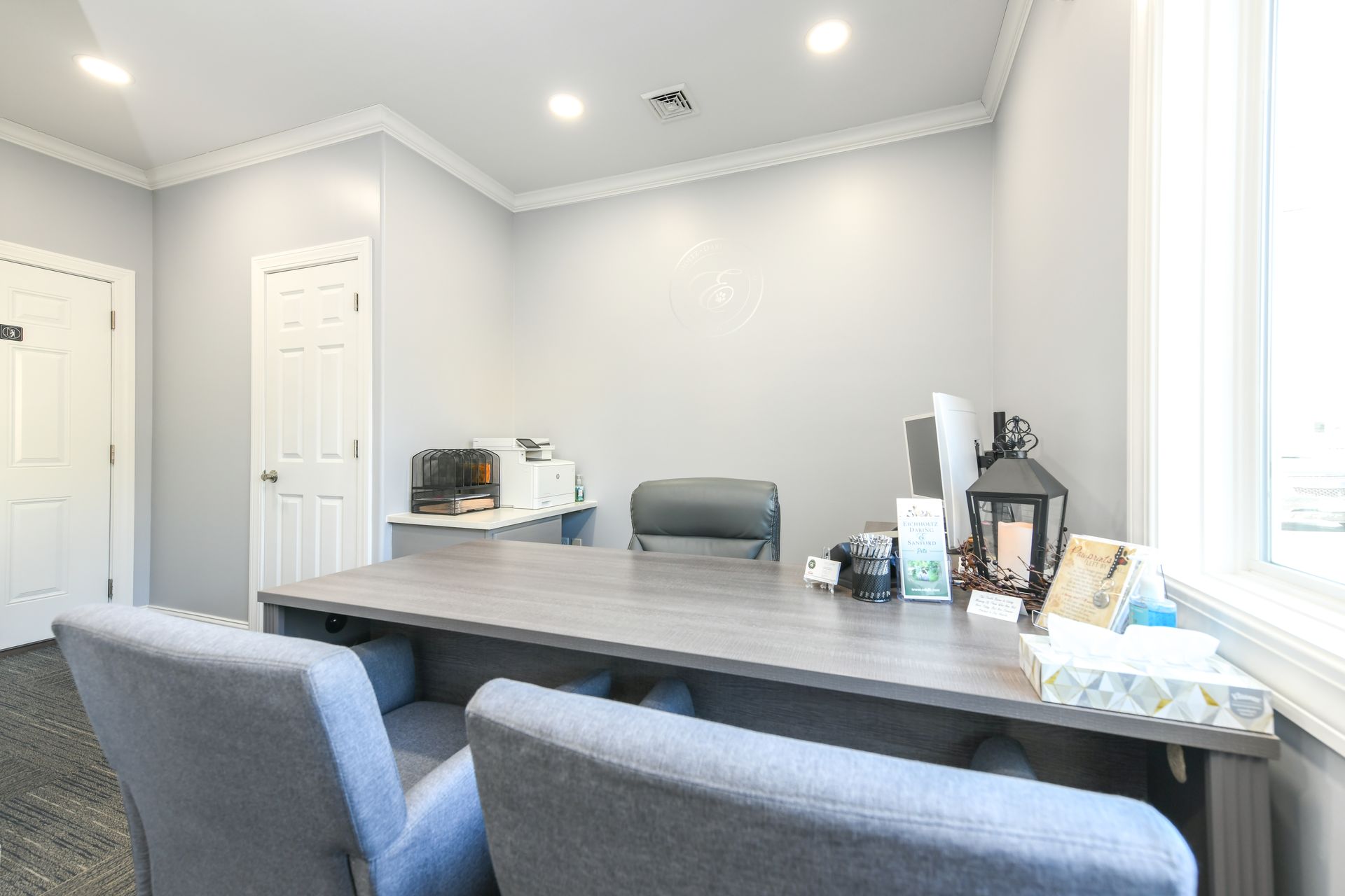 A room with a desk and two chairs in it.