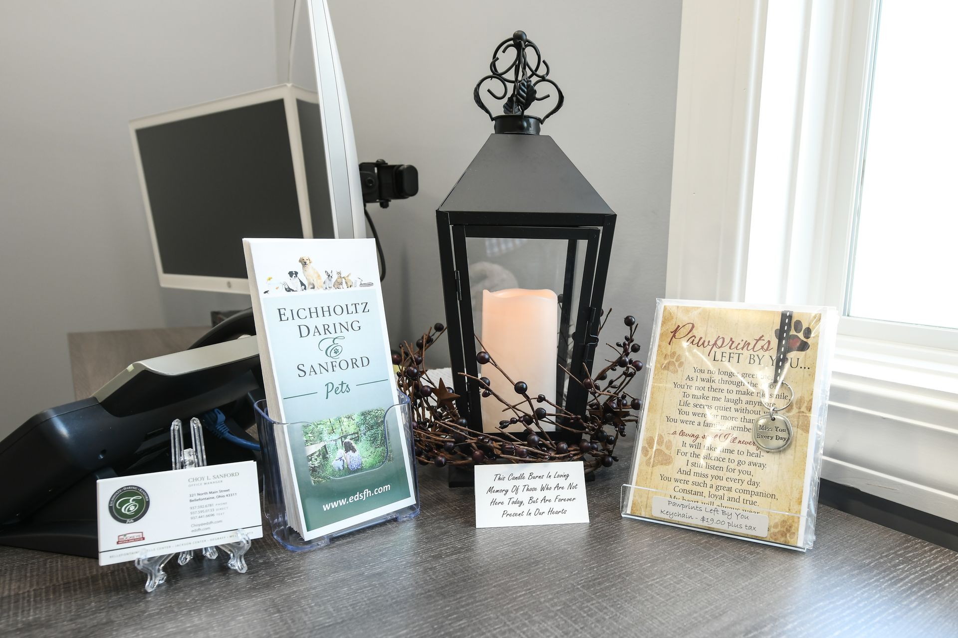 A lantern with a candle in it is on a table next to a computer