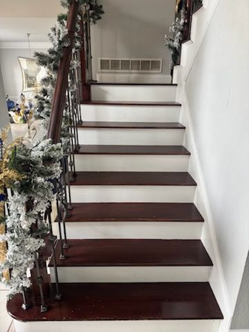 A wooden staircase with white steps and a wooden railing decorated for christmas