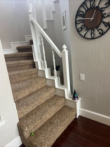 There is a clock on the wall above the stairs