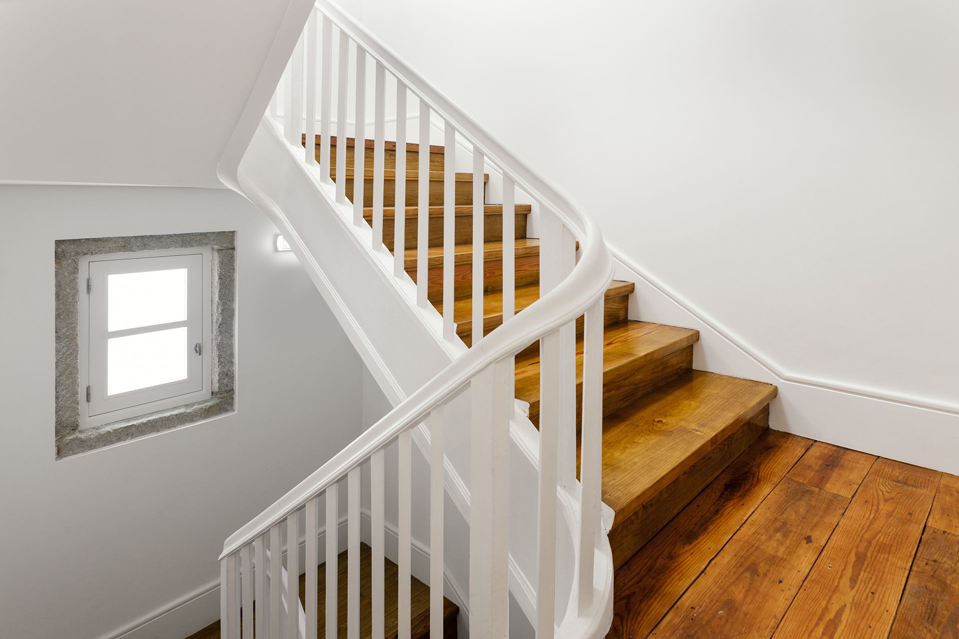 A wooden staircase with a white railing and a window.