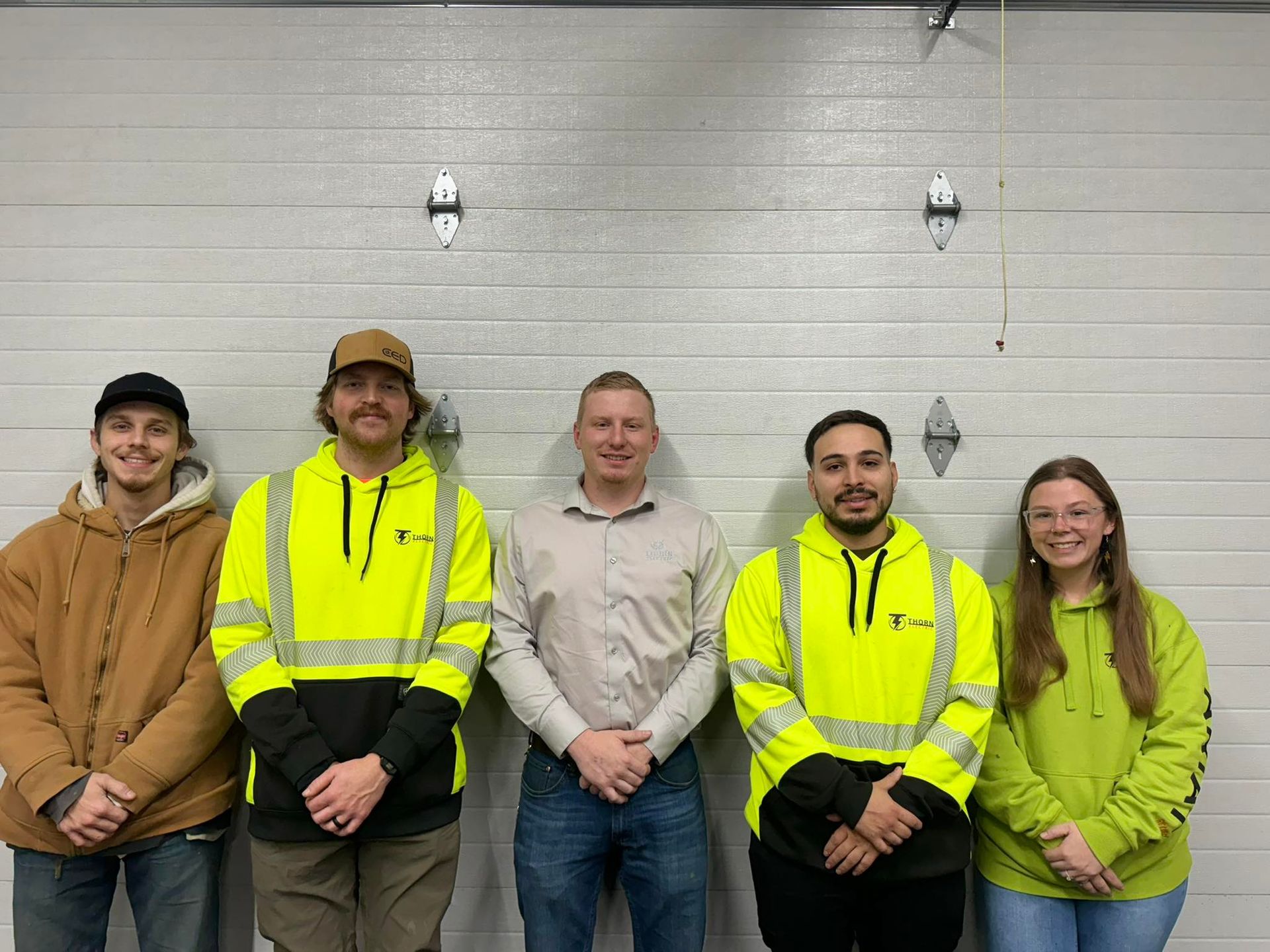 A group of people are posing for a picture in front of a garage door.