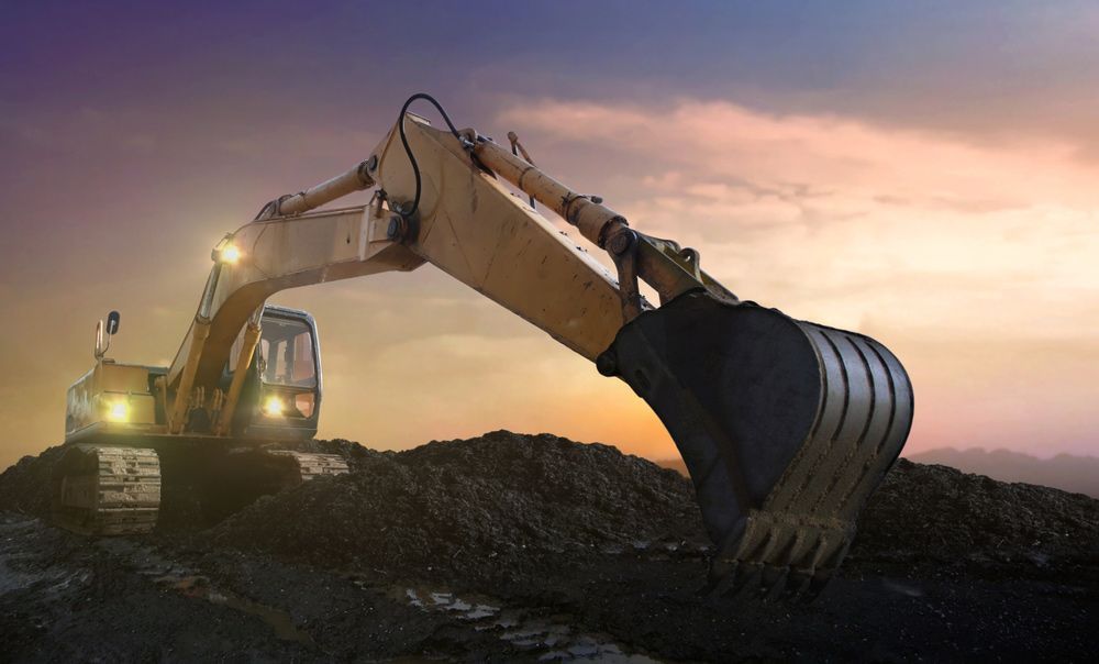 An Excavator Is Working On A Construction Site At Sunset — JJ's Excavator & Tipper Hire in Kingaroy, QLD