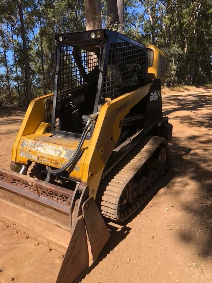 A Yellow Bulldozer Is Parked On A Dirt Road In The Woods — JJ's Excavator & Tipper Hire in Kingaroy, QLD