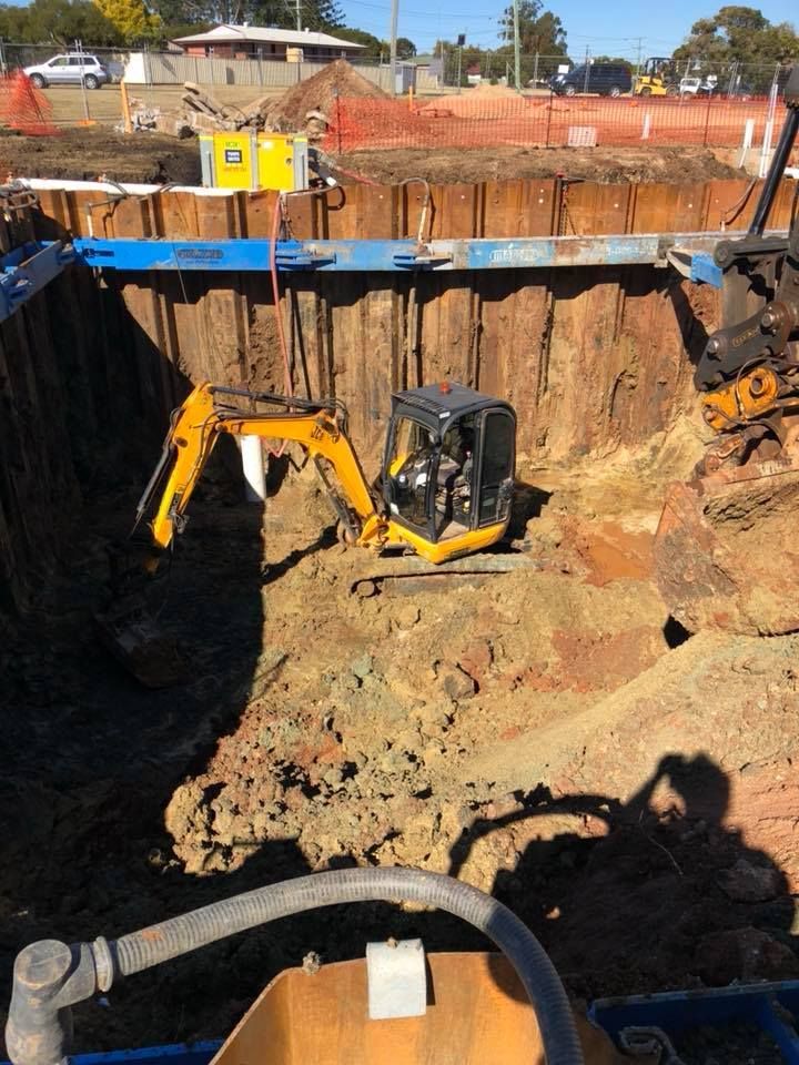 A Yellow Excavator Is Digging A Hole In A Construction Site — JJ's Excavator & Tipper Hire in Kingaroy, QLD