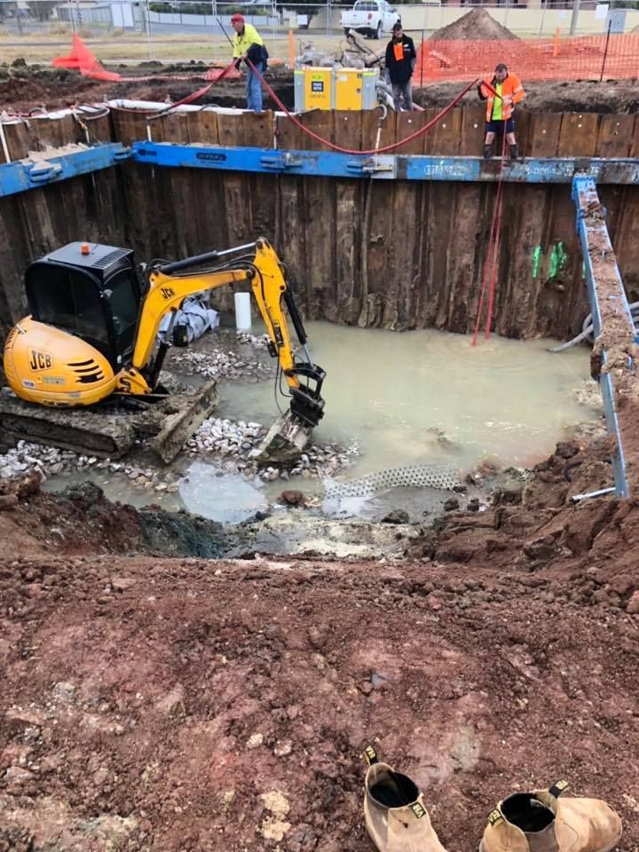 A Yellow Excavator Is Digging A Hole In The Ground — JJ's Excavator & Tipper Hire in Nanango, QLD
