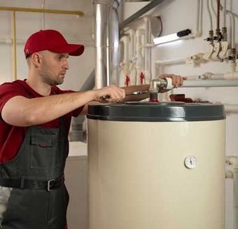 A man wearing a red shirt is shown fixing a water heater.