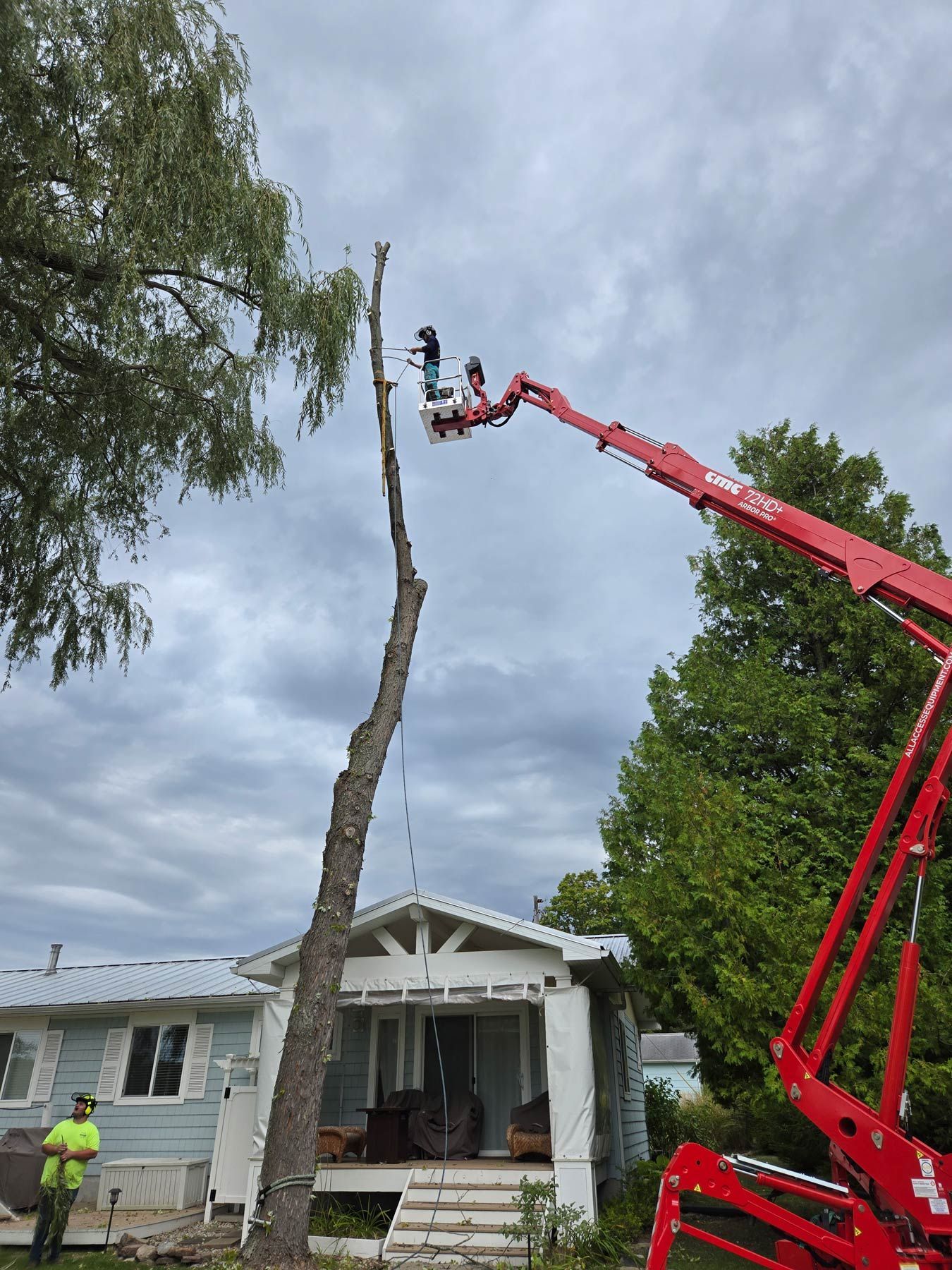 A crane is cutting a tree in front of a house - Gaylord, MI - Stuckman Tree Service