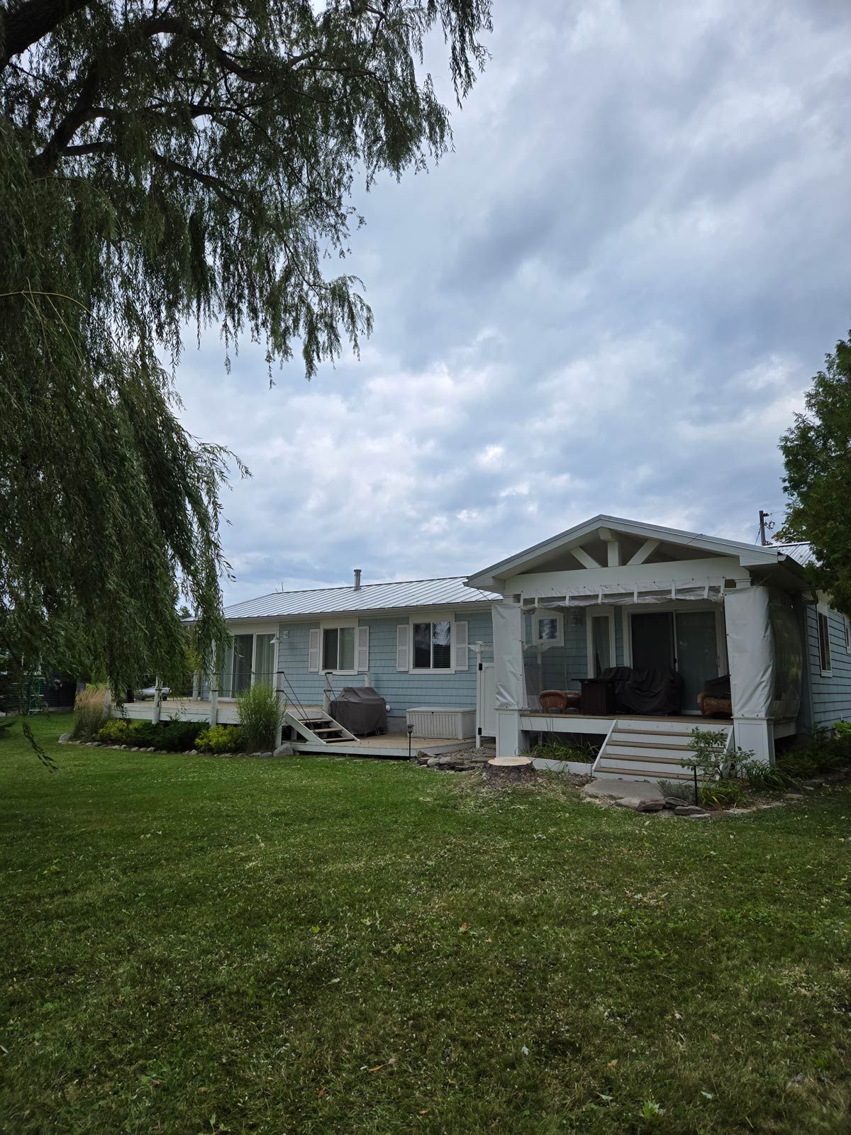 A white house with a porch and a large lawn in front of it - Gaylord, MI - Stuckman Tree Service