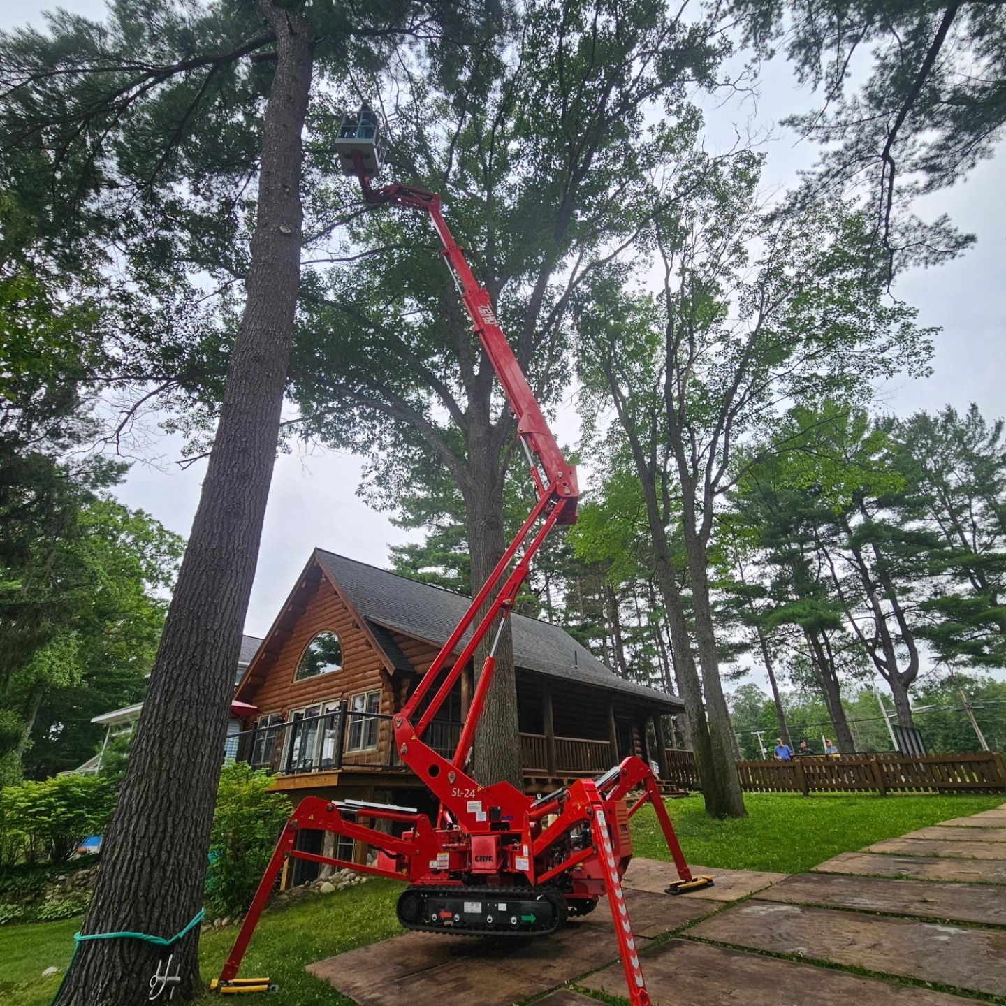 A red crane is sitting next to a tree in front of a house - Gaylord, MI - Stuckman Tree Service