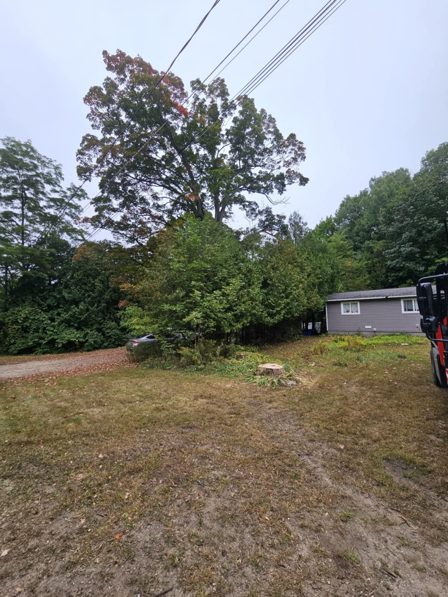 A motorcycle is parked in a dirt lot in front of a house.