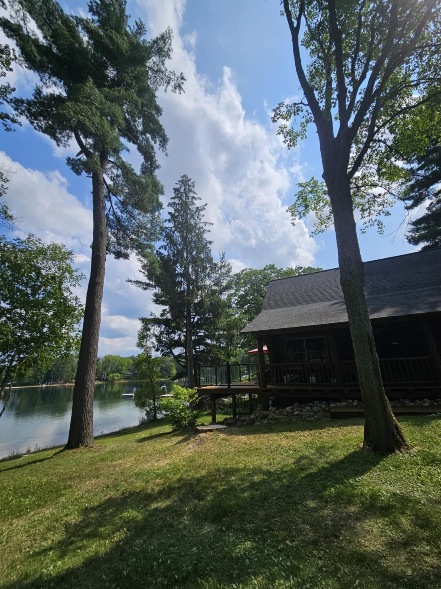 A cabin is sitting on the shore of a lake surrounded by trees.