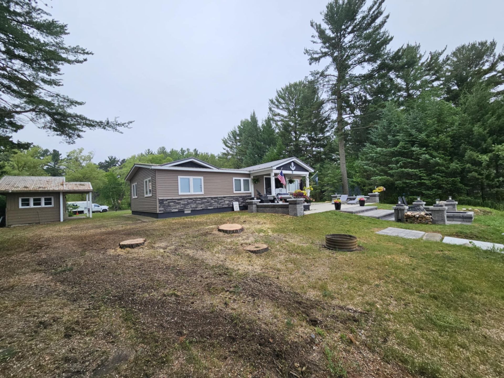 A mobile home is sitting in the middle of a grassy field surrounded by trees.