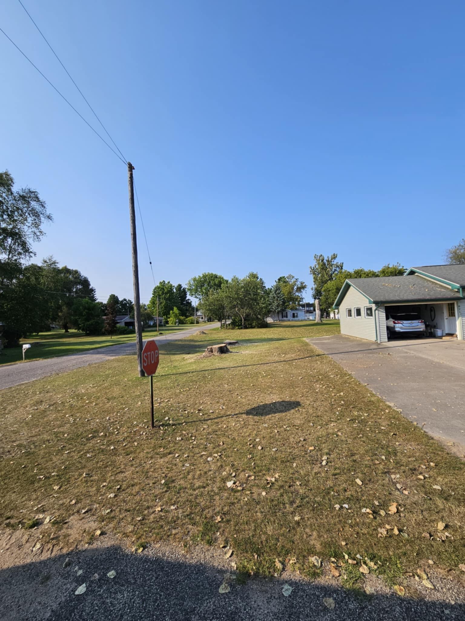 A house is sitting in the middle of a grassy field next to a road.