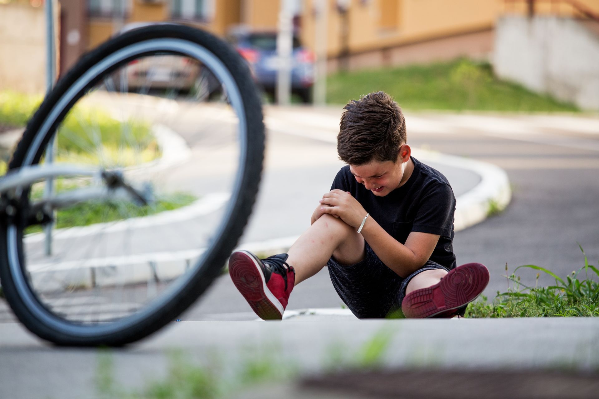 Boy with hurt knee sitting next to his bicycle