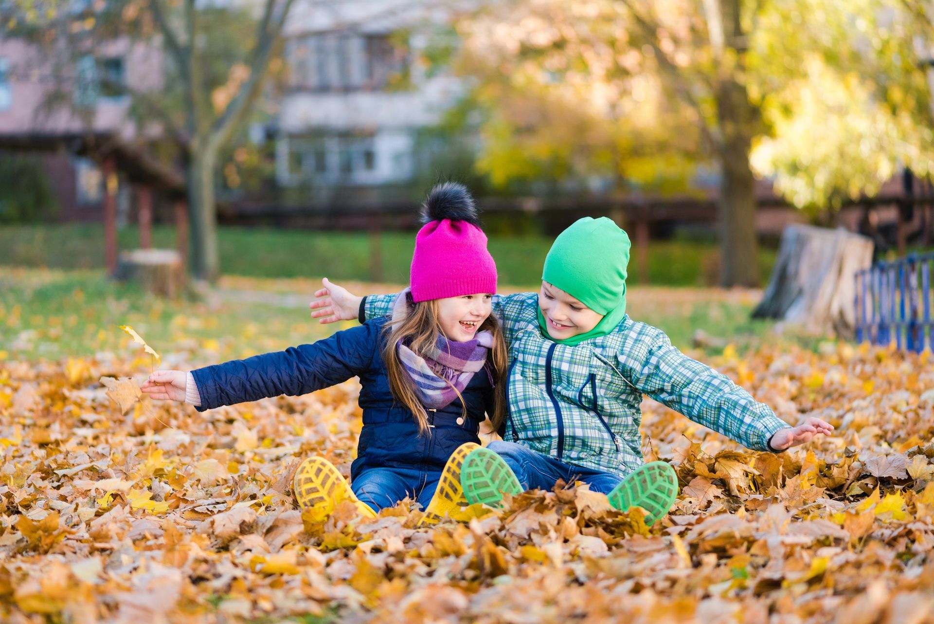 Two children laughing and playing in leaves