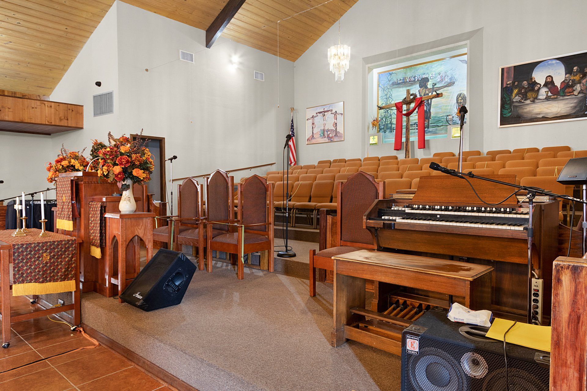 Interior of a church sanctuary with chairs, organ, stage, and stained-glass window.