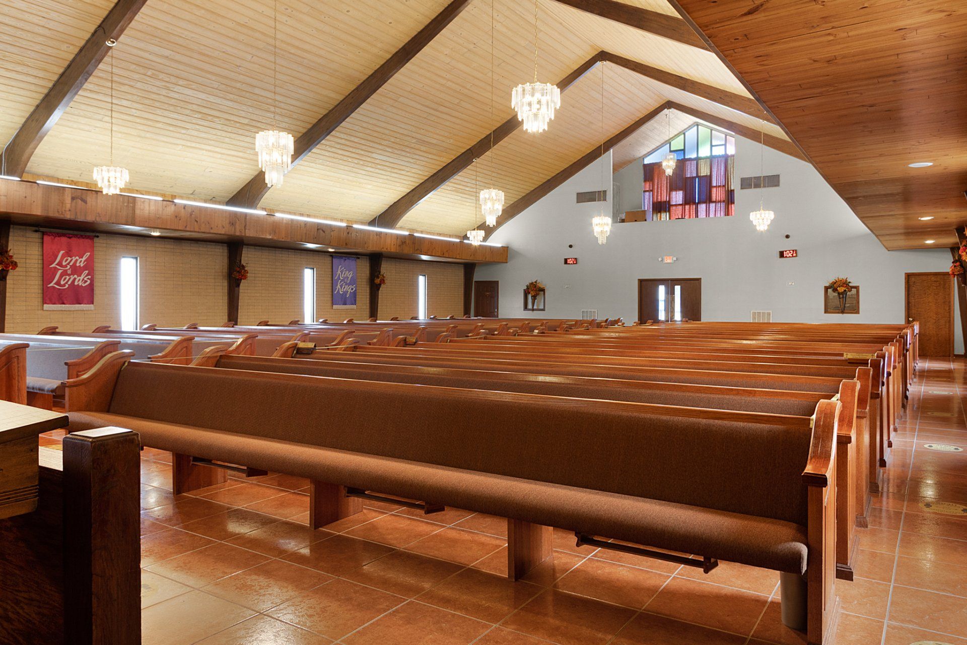Interior of a church with wooden pews, high ceiling, and stained glass windows.