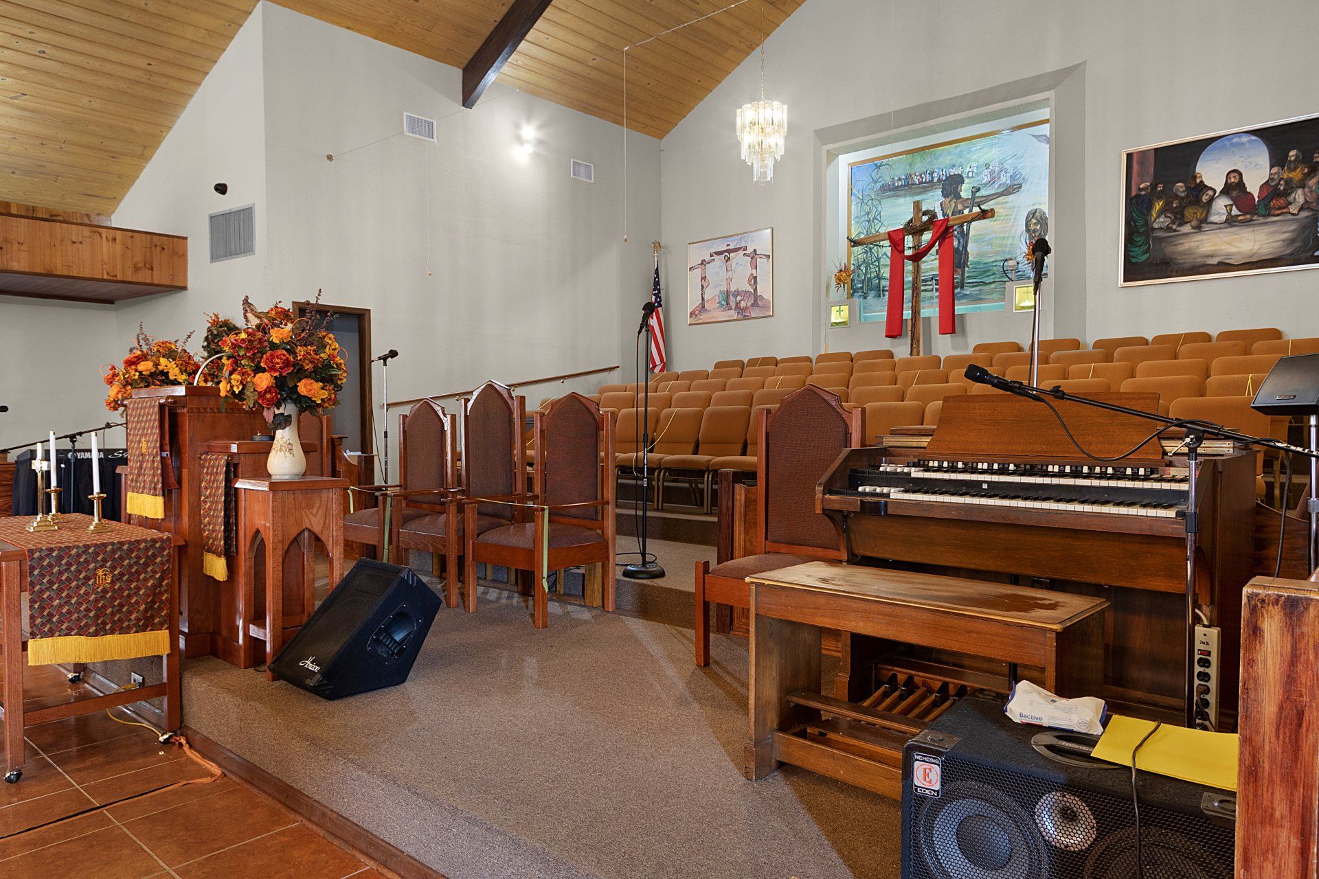 Interior of a church sanctuary with pews, organ, microphones, and a cross.