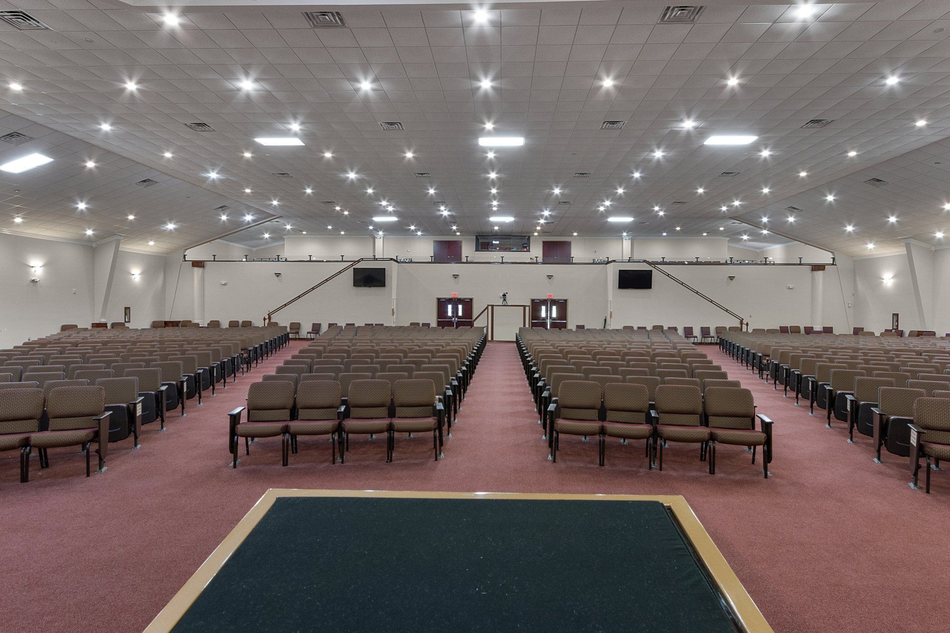 Empty church auditorium with rows of brown seats and a stage.