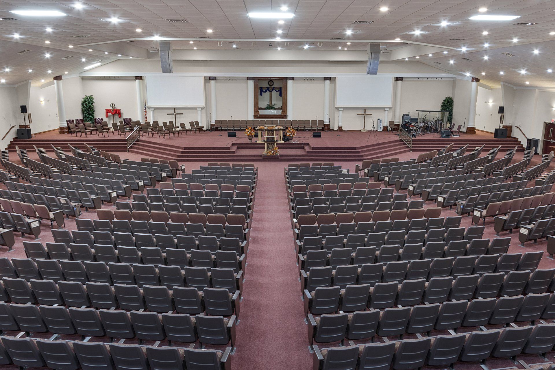 Large church auditorium with rows of seating facing a raised stage with crosses and an altar.
