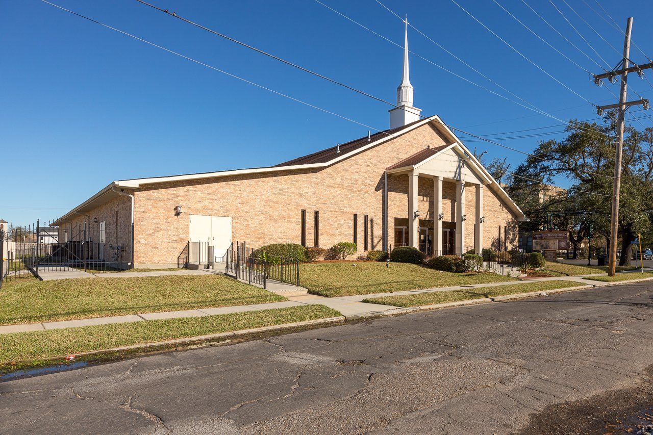 Brick church building with white steeple, blue sky, and green grass.
