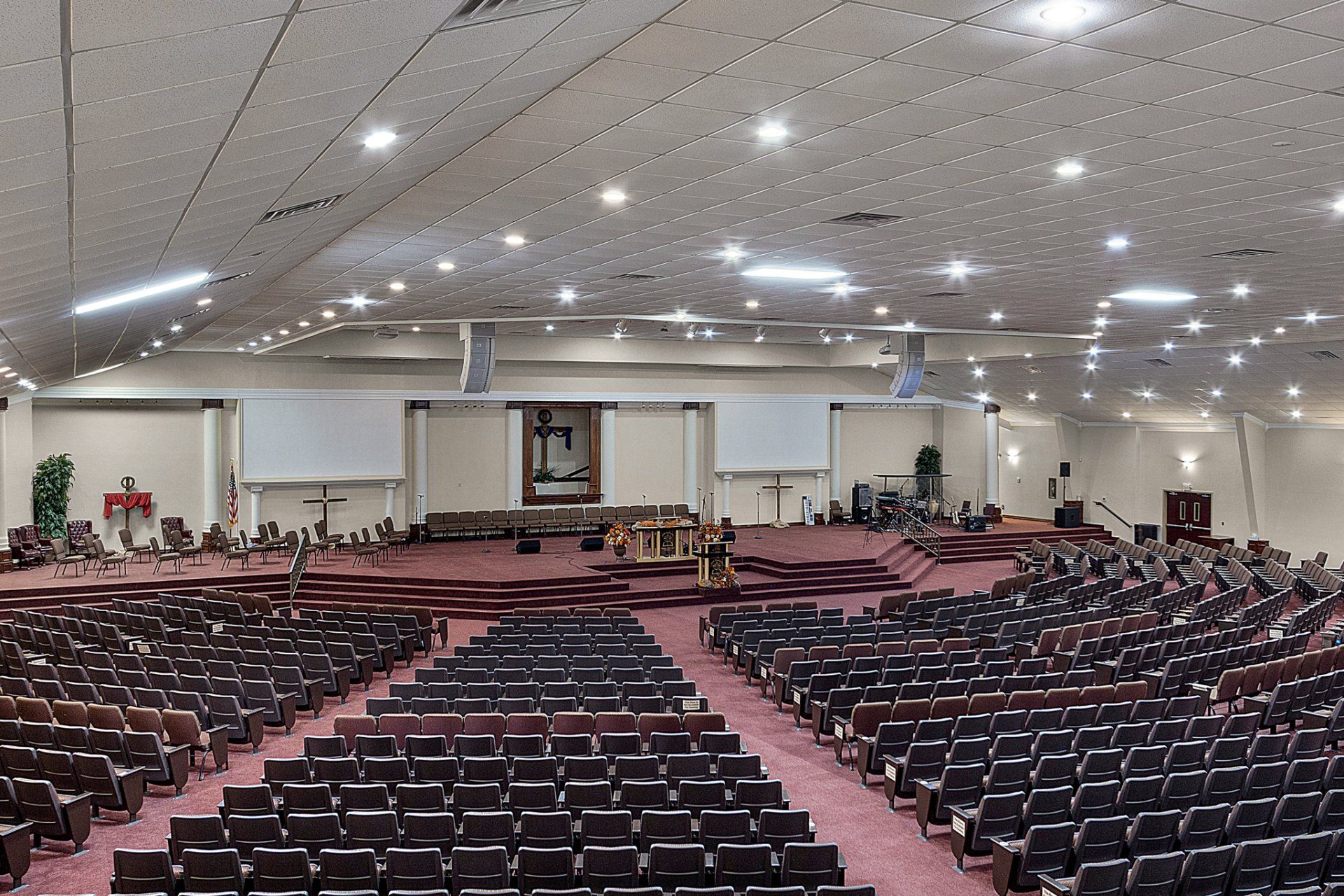 Large auditorium with rows of seating facing a stage; stage has a pulpit and backdrop.