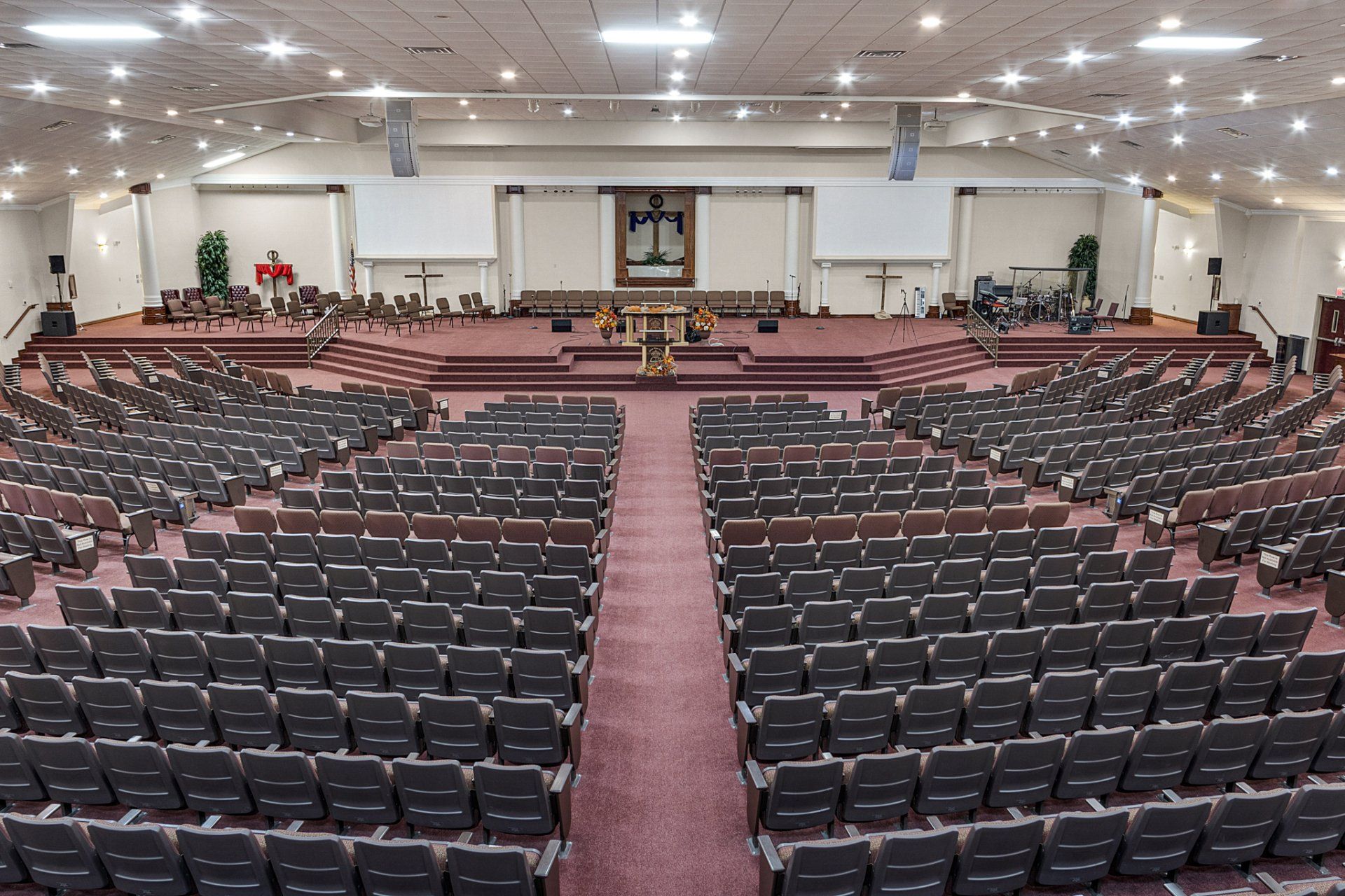 Large church interior with rows of seating, stage at front, and overhead lighting.