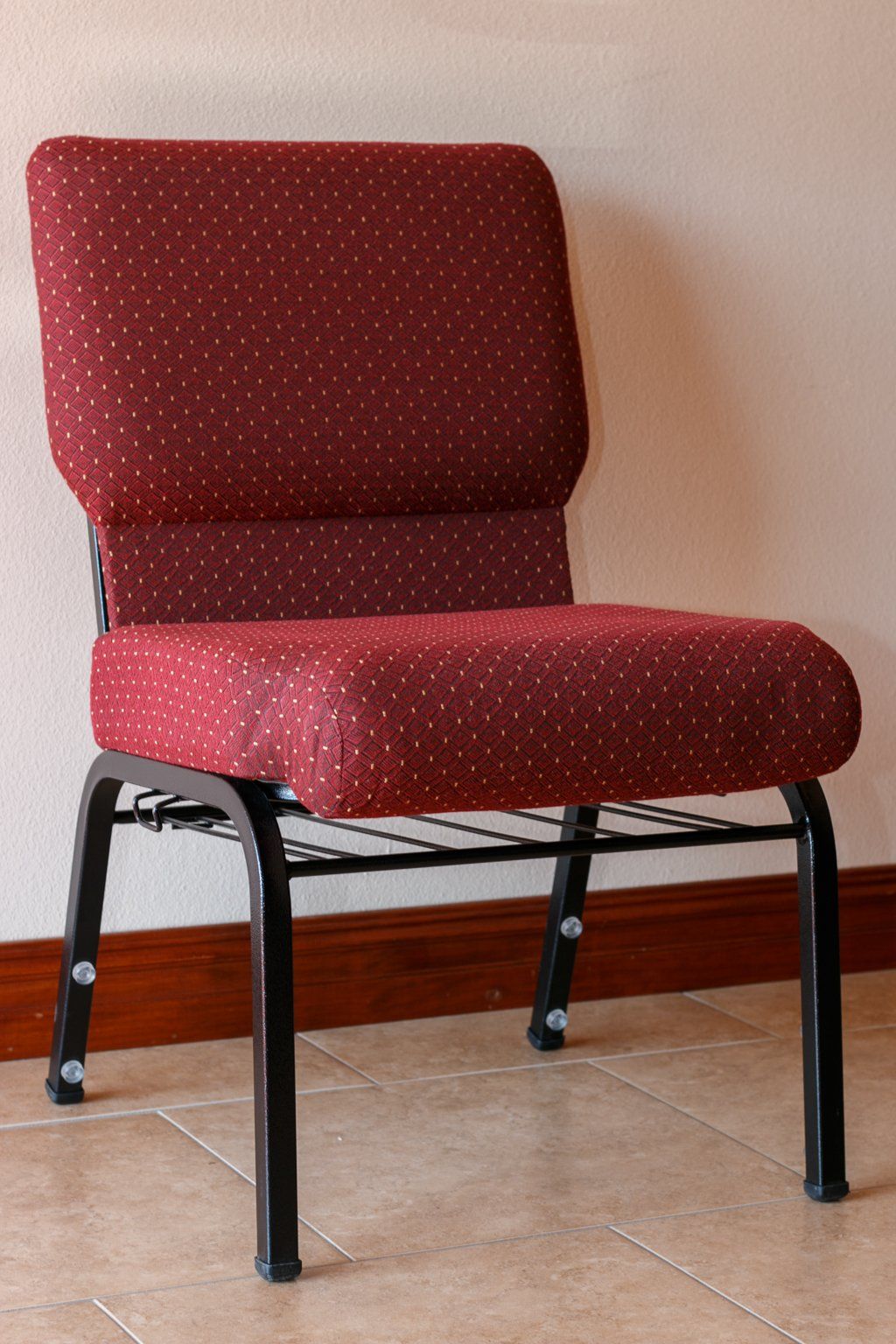 Red upholstered chair with black metal frame, on tiled floor.