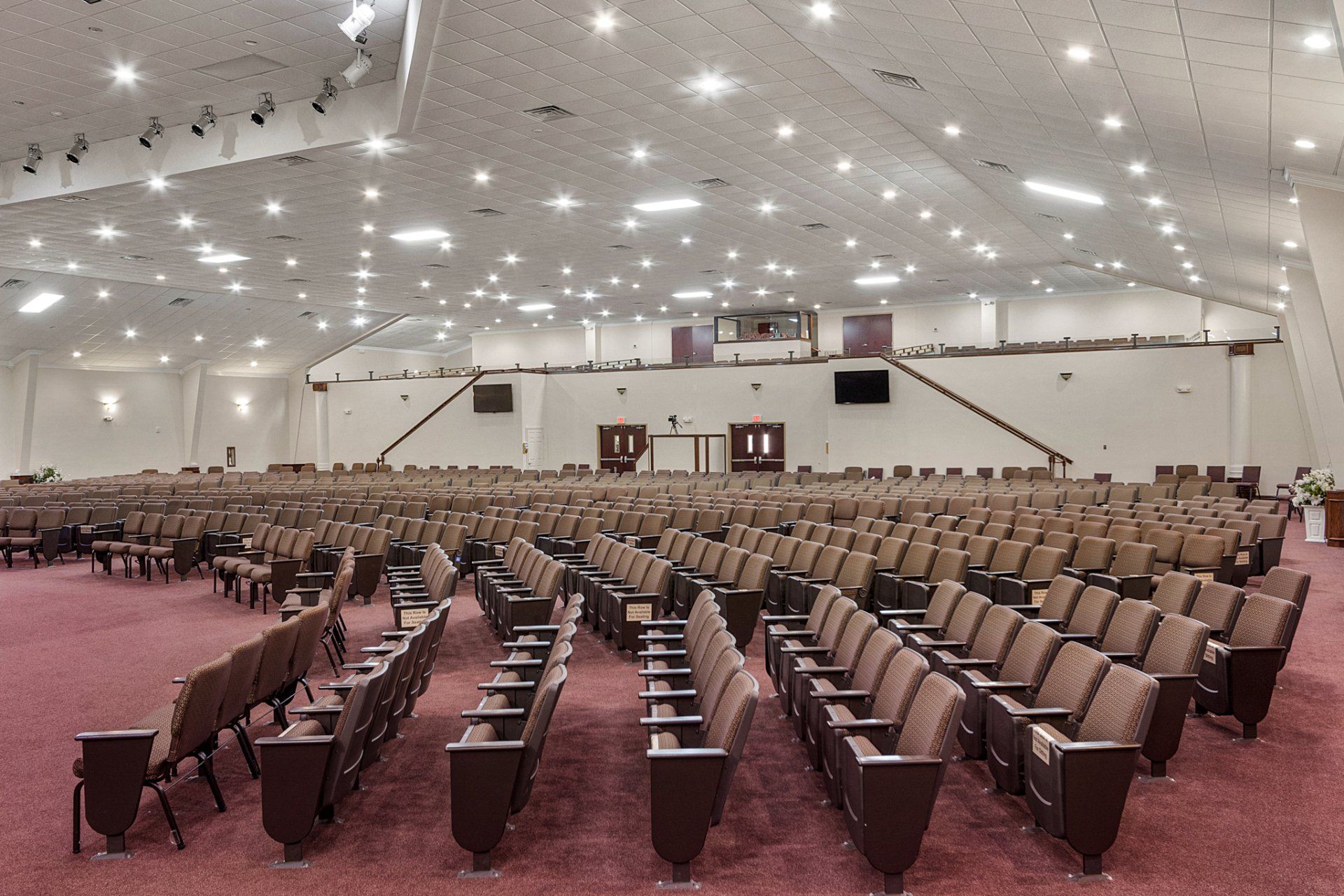 Large auditorium with rows of brown seats, stage in the back, and overhead lights.