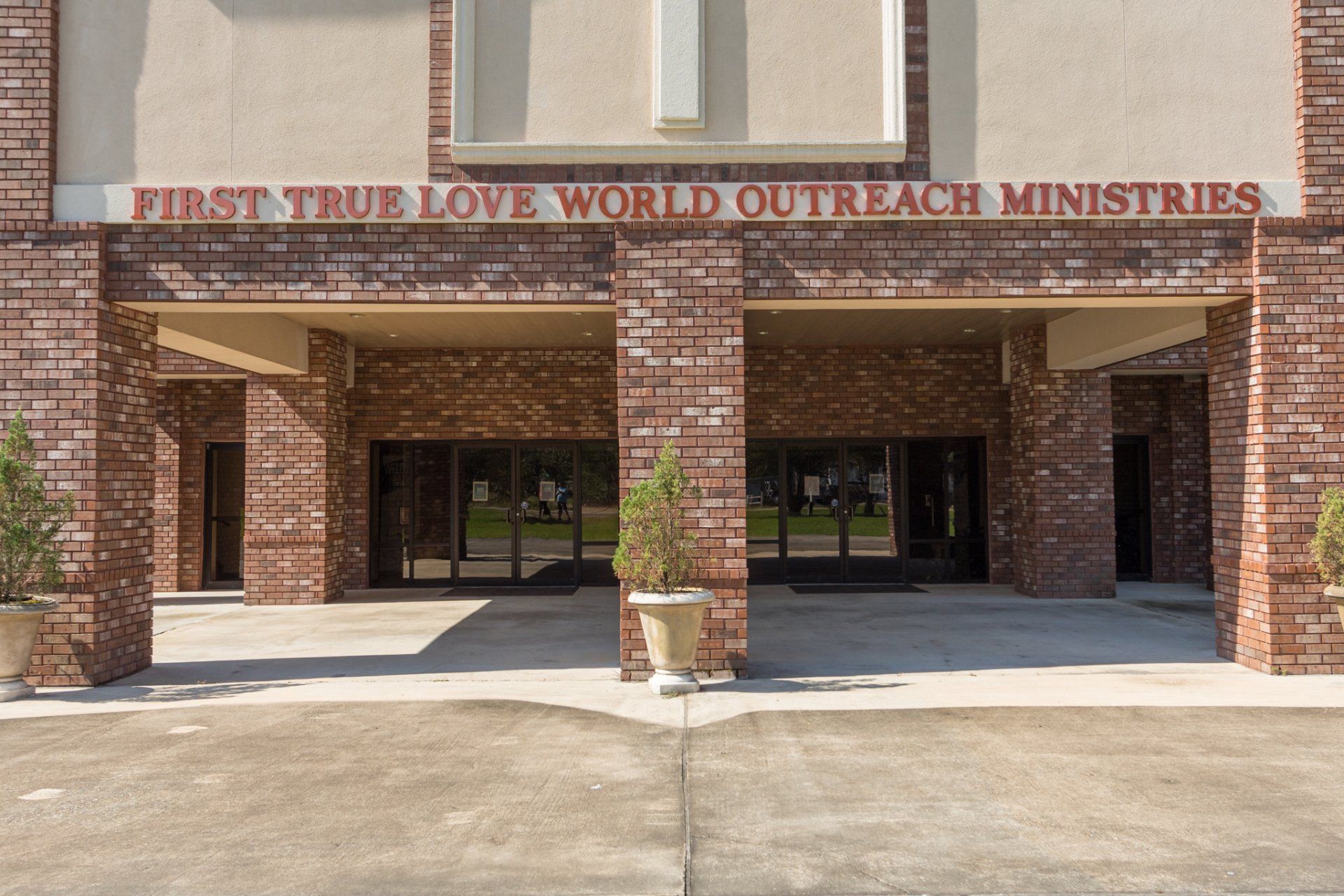Entrance to First True Love World Outreach Ministries, red brick building, glass doors, tan accents.