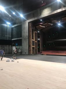 A large empty auditorium with a wooden floor and a stage.