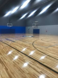 A basketball court with a wooden floor and a basketball hoop.