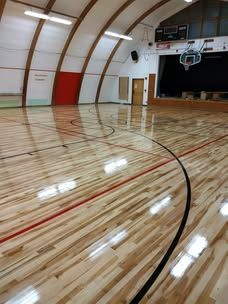 A basketball court with a wooden floor and a basketball hoop.