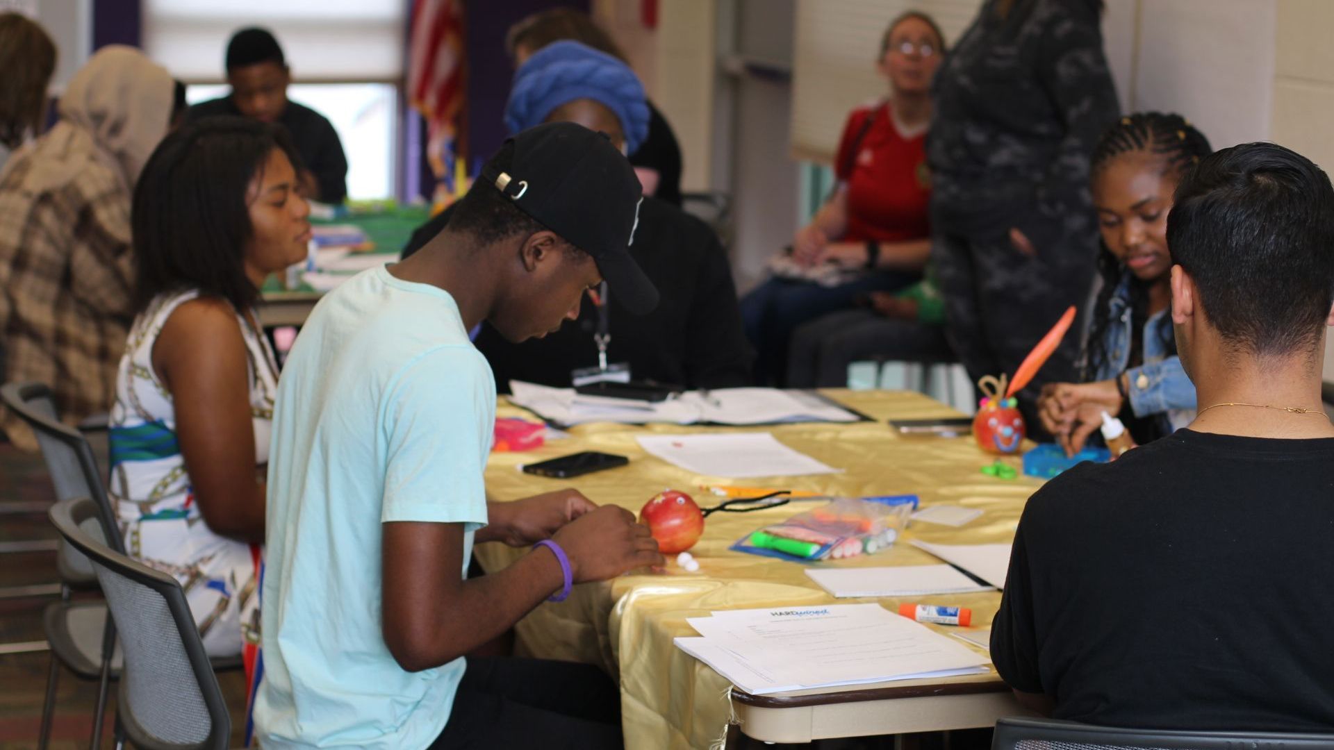 Conceptual Change Theory: A group of people are sitting around a table making crafts.