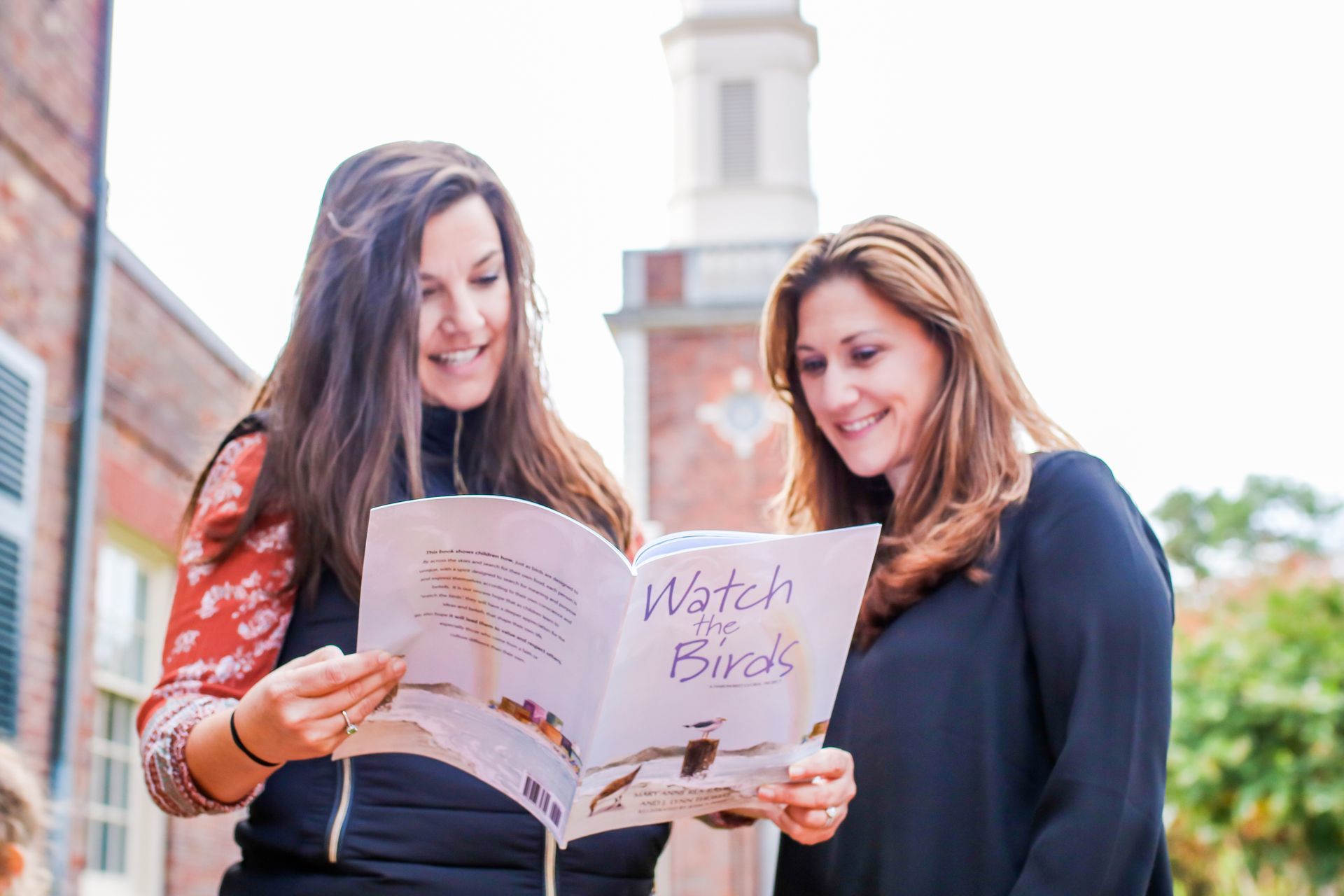 Programs for Refugees: Two women are standing next to each other looking at a book.