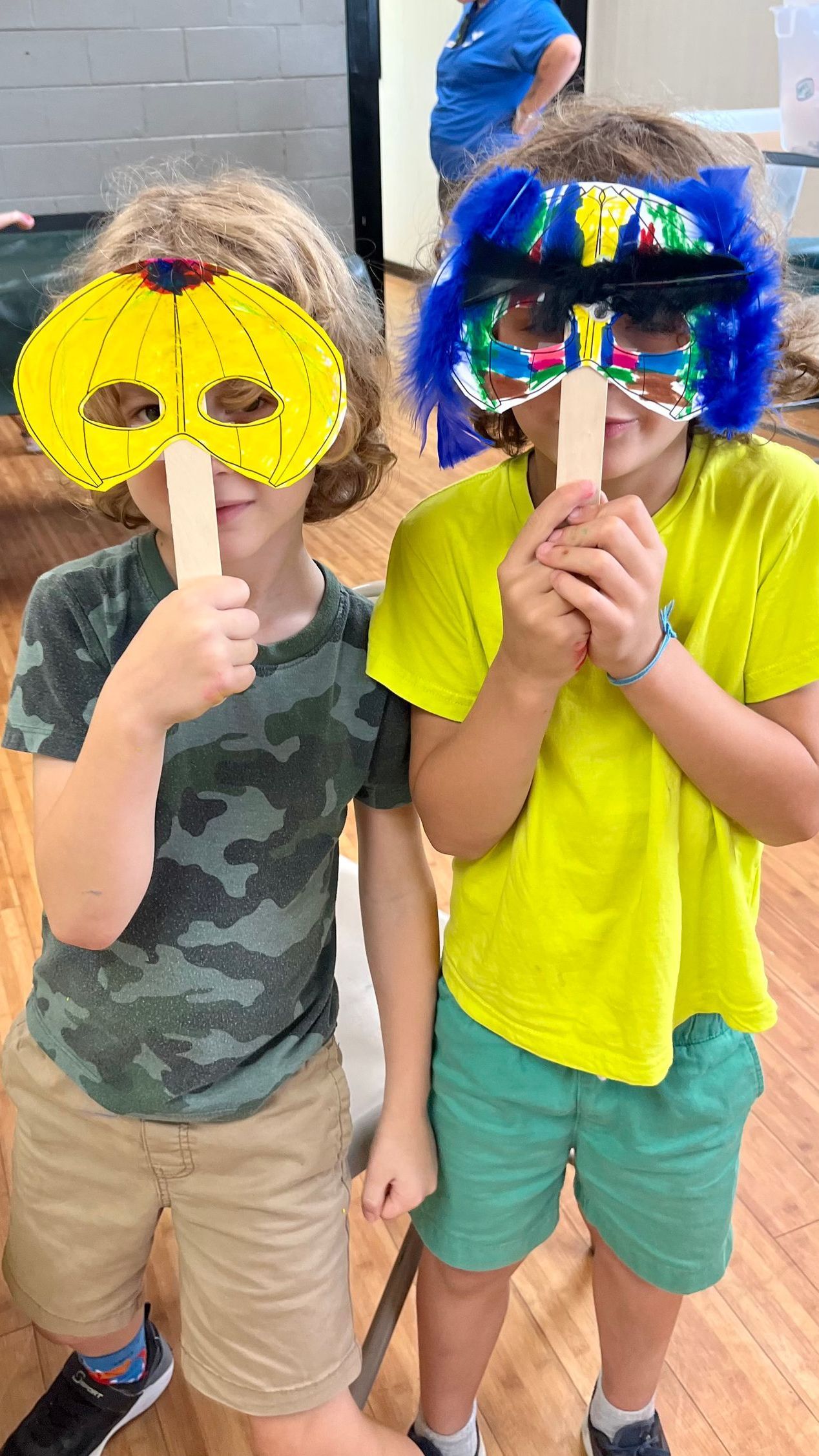 Conceptual Change Theory: Two young boys wearing masks made out of wood are standing next to each other.