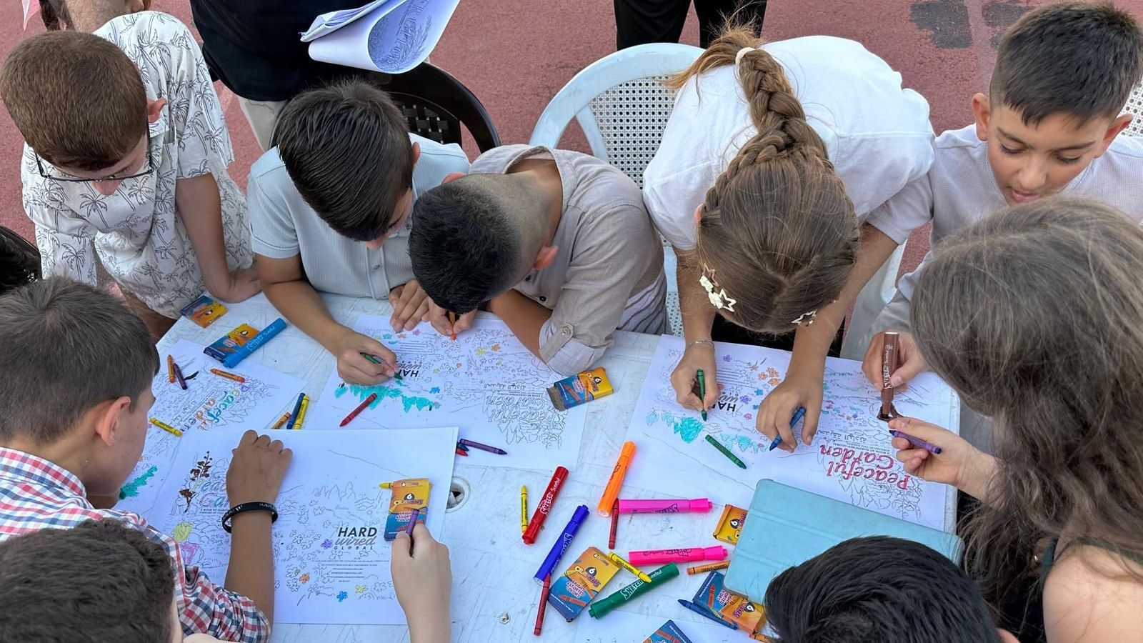 Conceptual Change Theory: A group of children are sitting around a table drawing with crayons.