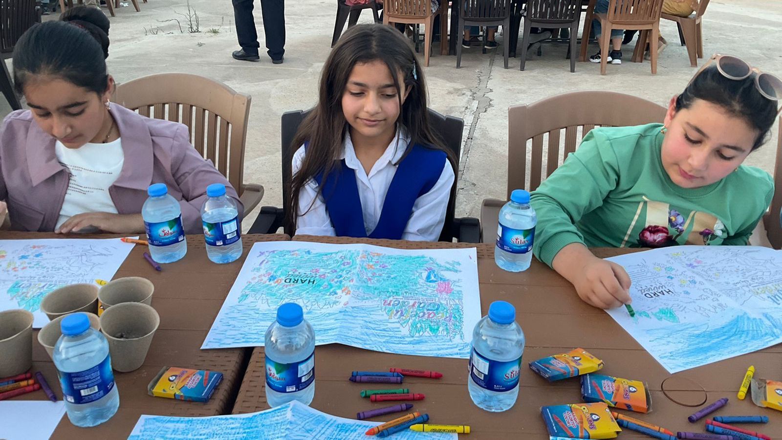 Alternatives to DEI Training: Three young girls are sitting at a table with water bottles and crayons.