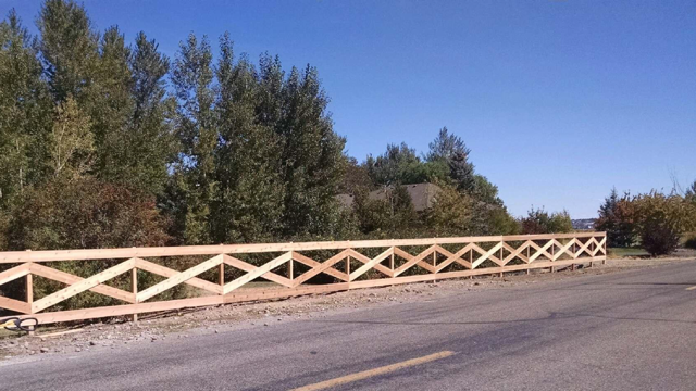 Gray slatted fence panel with a narrow yellow object peeking through the gap
