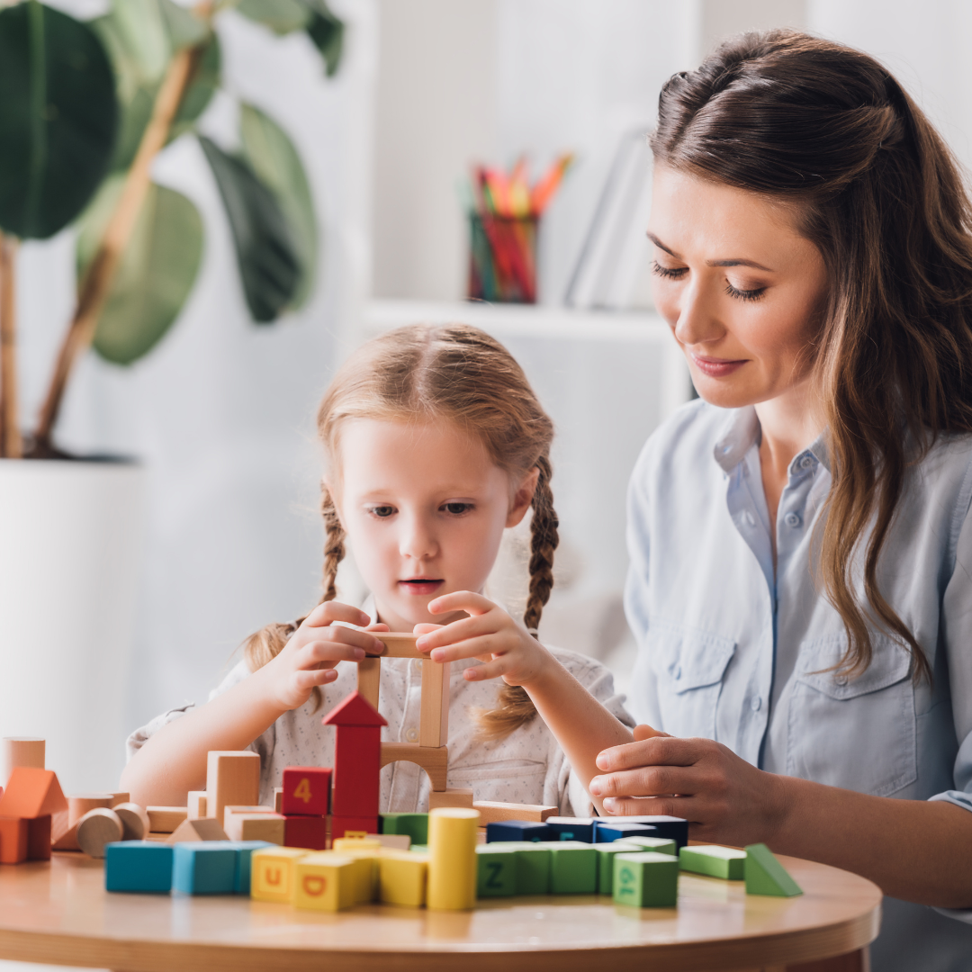 A teacher and child playing with building blocks.